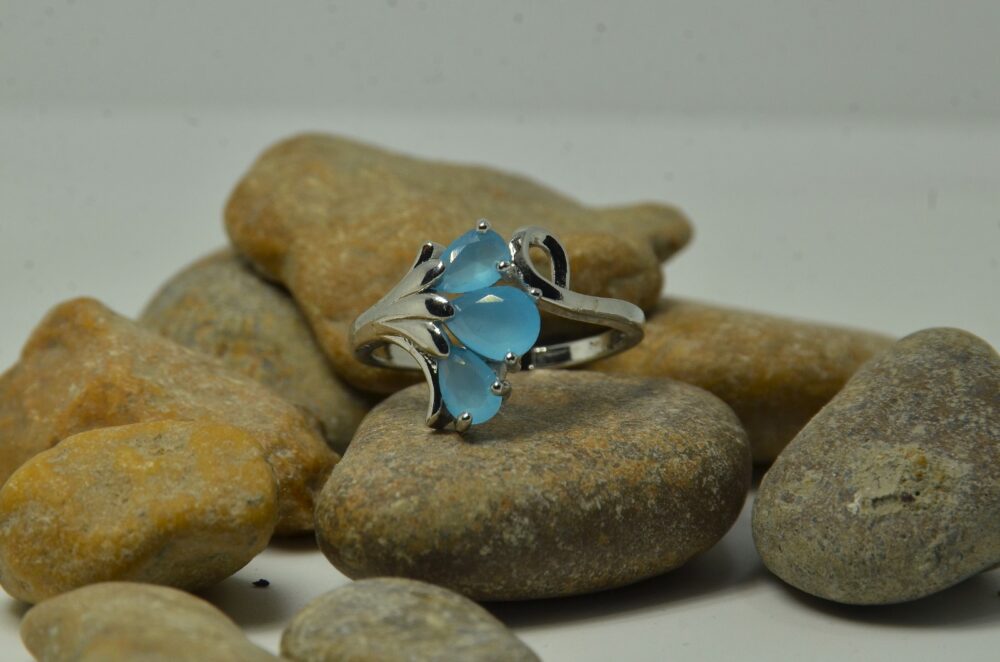 Elegant silver ring featuring three pear-shaped blue zircon stones in a floral-inspired design.