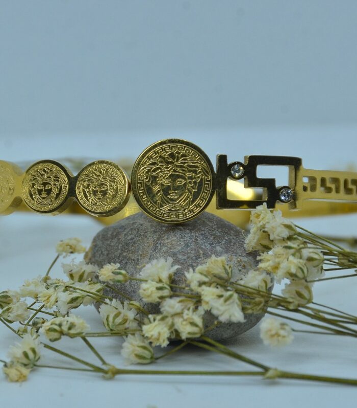 Gold-plated bracelet adorned with engraved Medusa-style coin motifs and a geometric clasp accented
