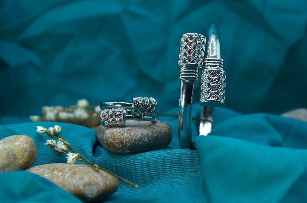 Elegant silver jewelry set featuring a bracelet and matching rings adorned with red and white gemstones in a lattice design. - Image 2
