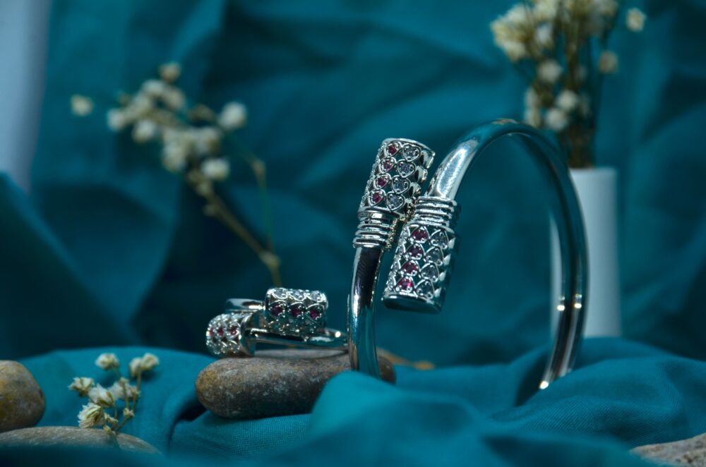 Elegant silver jewelry set featuring a bracelet and matching rings adorned with red and white gemstones in a lattice design.