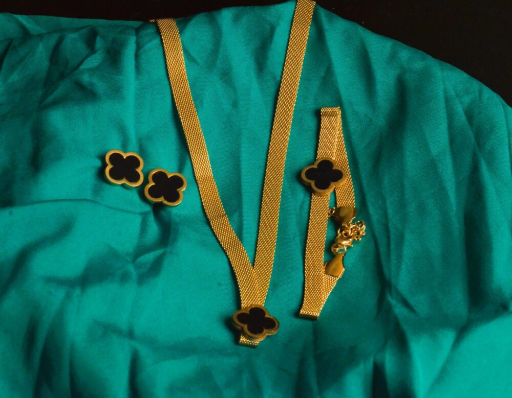 Chic gold jewelry set featuring a clover motif with black enamel accents on a textured chain. - Image 4