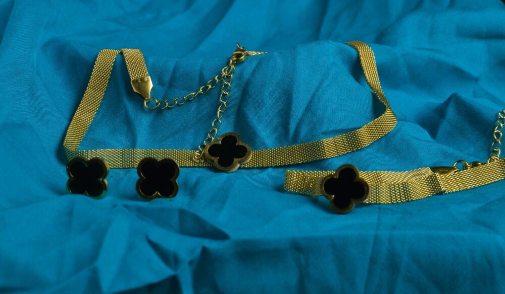 Chic gold jewelry set featuring a clover motif with black enamel accents on a textured chain. - Image 3
