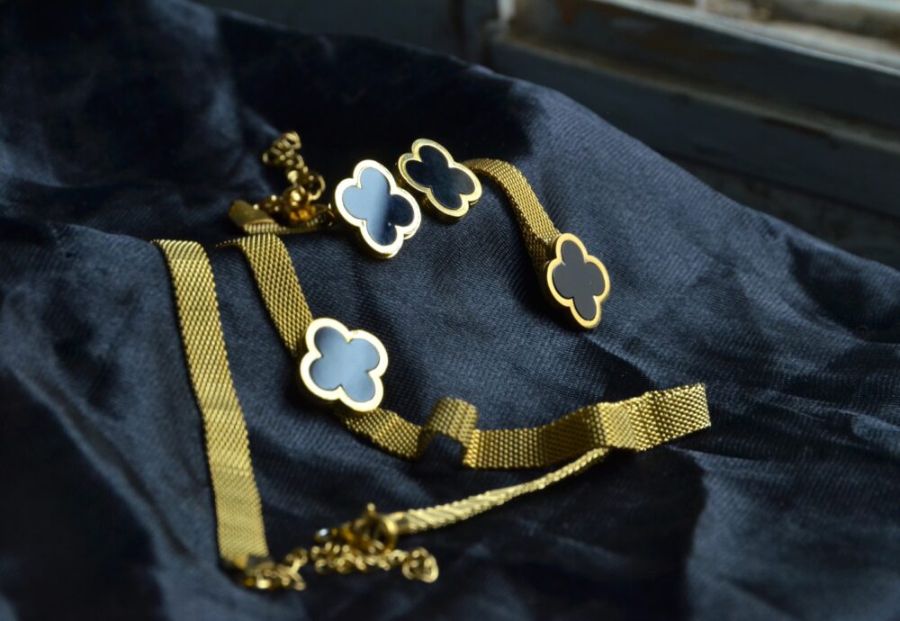 Chic gold jewelry set featuring a clover motif with black enamel accents on a textured chain. - Image 2