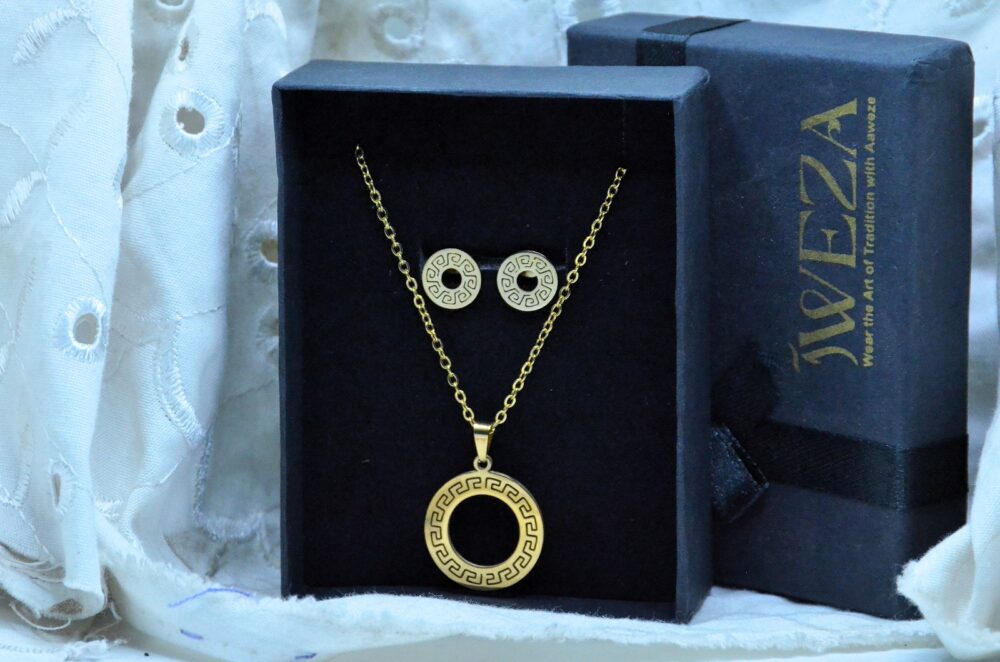 Classic gold jewelry set featuring a circular pendant and matching earrings with intricate Greek key patterns.
