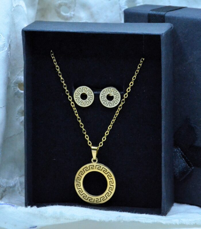 Classic gold jewelry set featuring a circular pendant and matching earrings with intricate Greek key patterns.