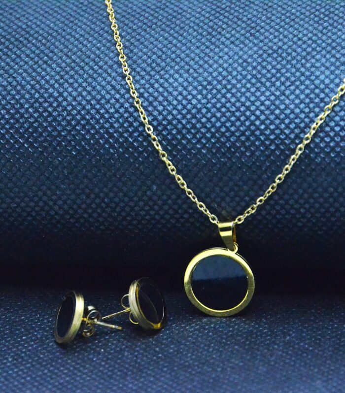 Elegant gold jewelry set with a round black enamel pendant and matching stud earrings