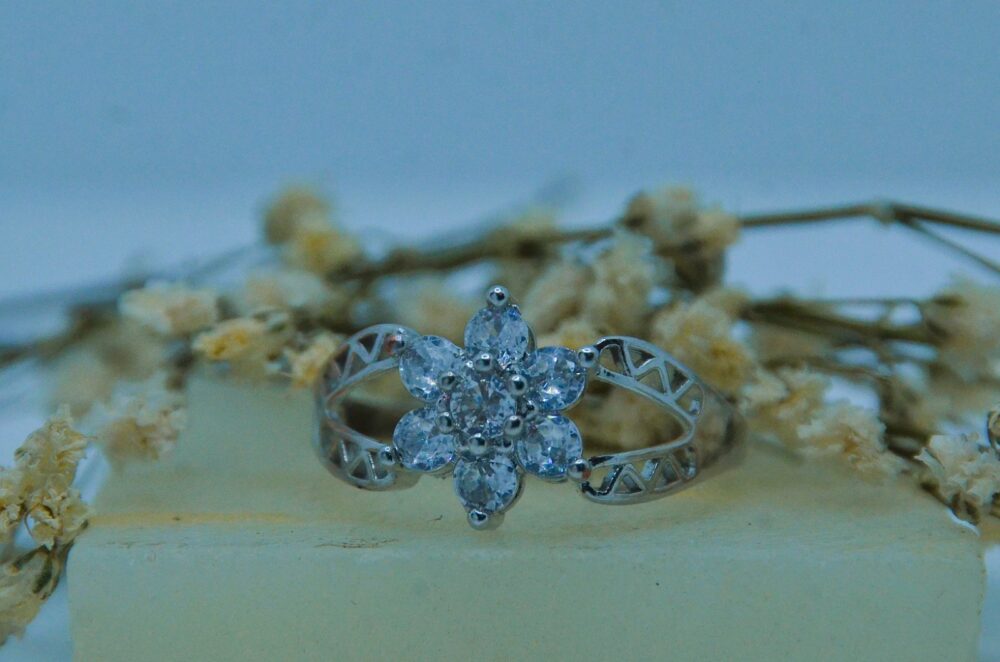 Delicate silver ring featuring a floral cluster of sparkling round-cut zircon stones with a filigree band design.