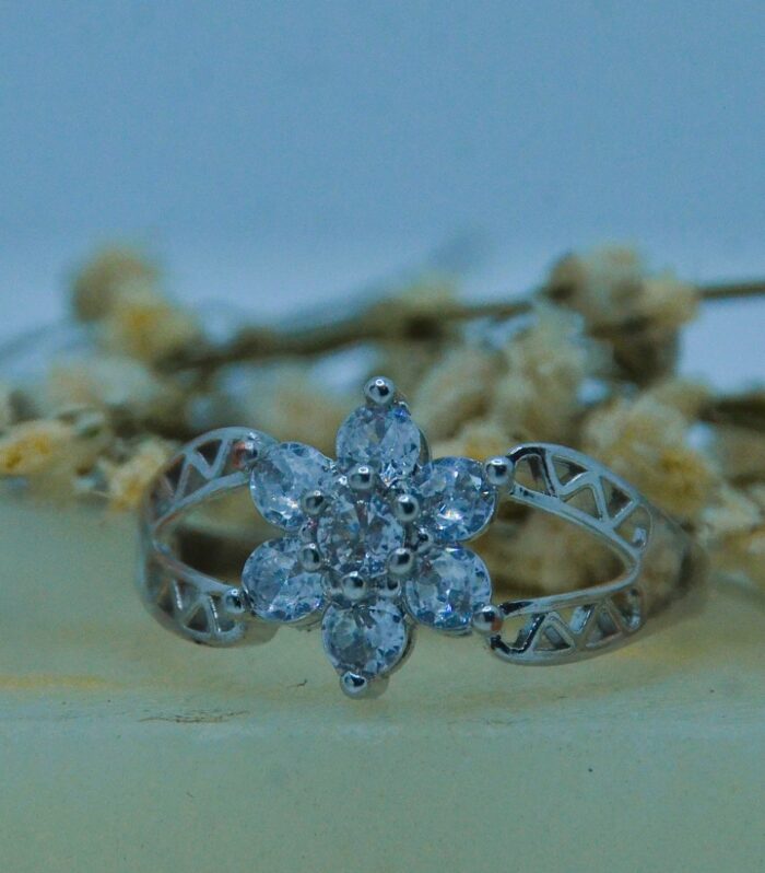 Delicate silver ring featuring a floral cluster of sparkling round-cut zircon stones with a filigree band design.