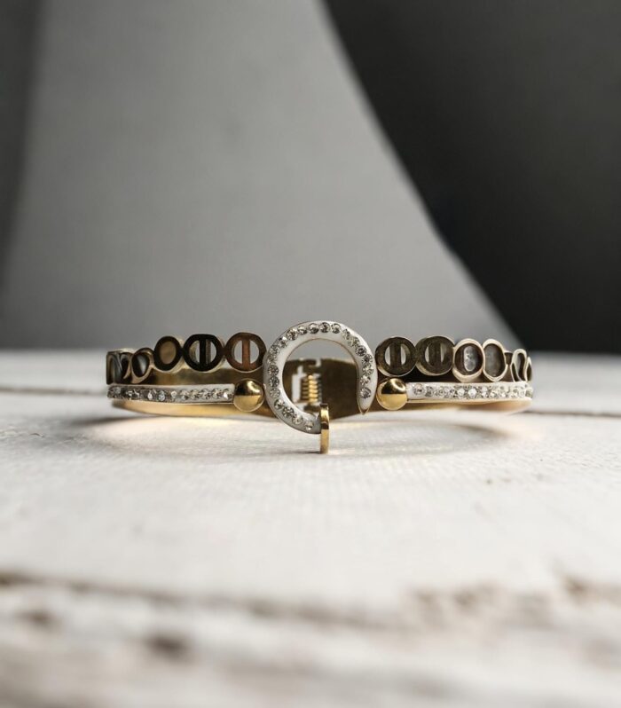 Stylish gold and silver-toned bracelet pair featuring screw motifs and a sparkling circular charm centerpiece.